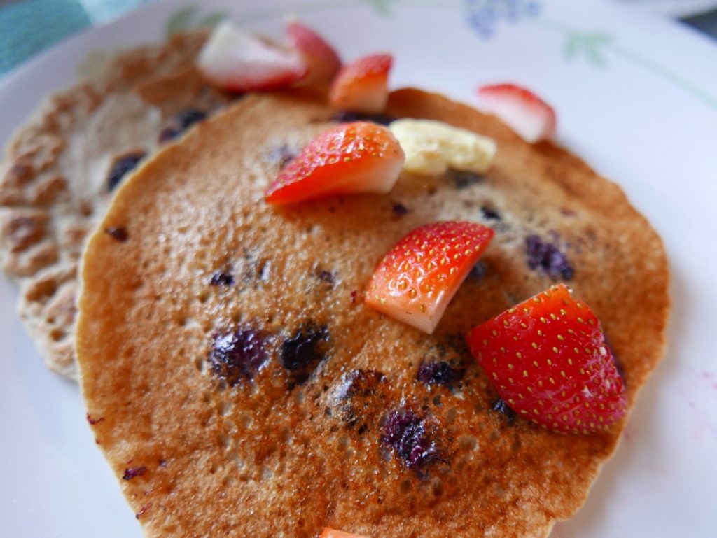 blueberry pancakes sprinkled wth sliced strawberries
